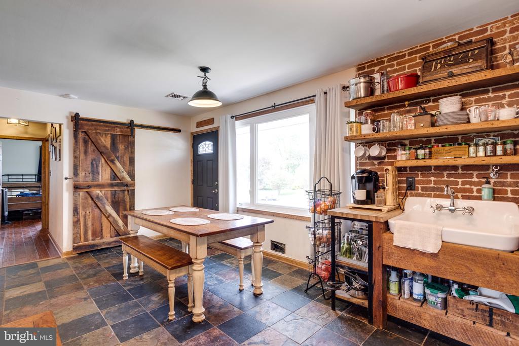 Kitchen with exposed brick shelving, apron-front sink, and farmhouse dining table.