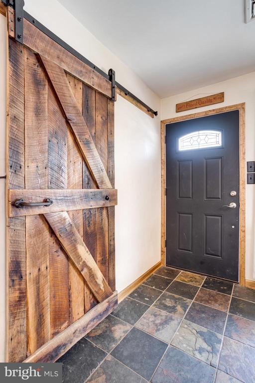 Entryway with a dark front door, rustic sliding barn door, and slate tile floor.