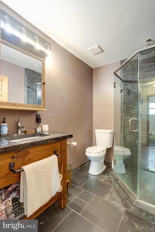 Bathroom with a wood vanity, white toilet, and glass-enclosed tiled shower.
