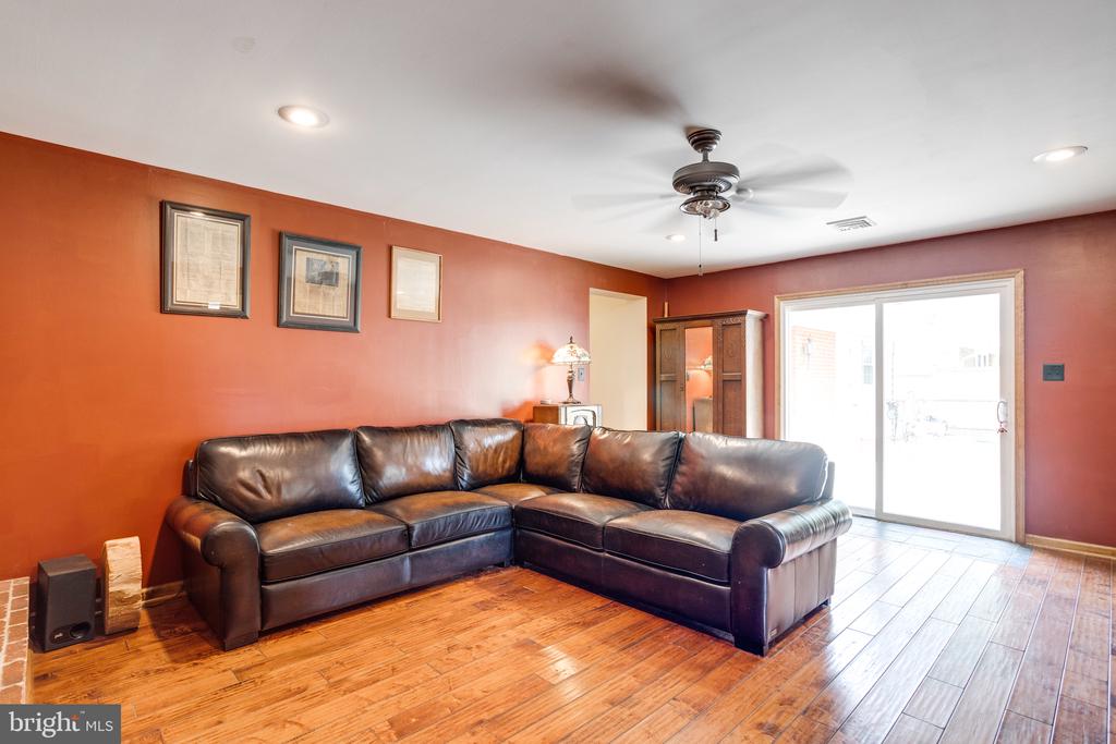 Living room with a dark leather sectional, rust-red walls, and hardwood floors.