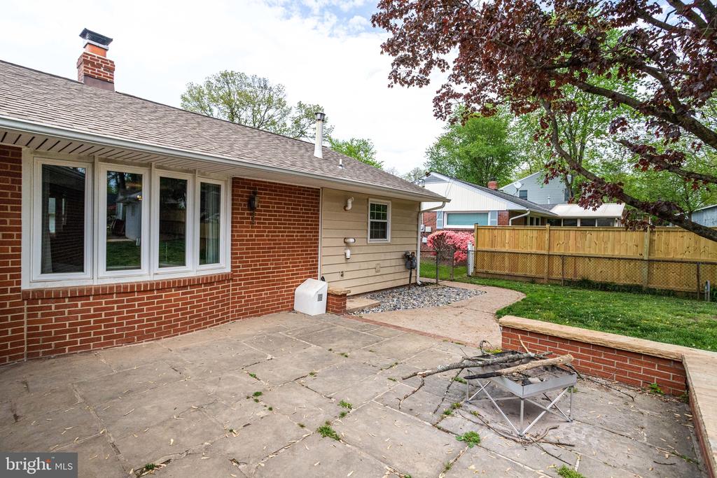 Home exterior with a paved patio, small fire pit, and fenced backyard.