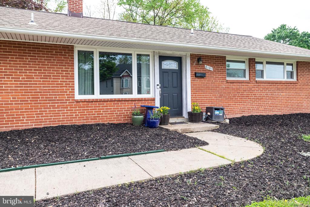 Red brick home with a dark front door, flower pots, and a curved walkway.