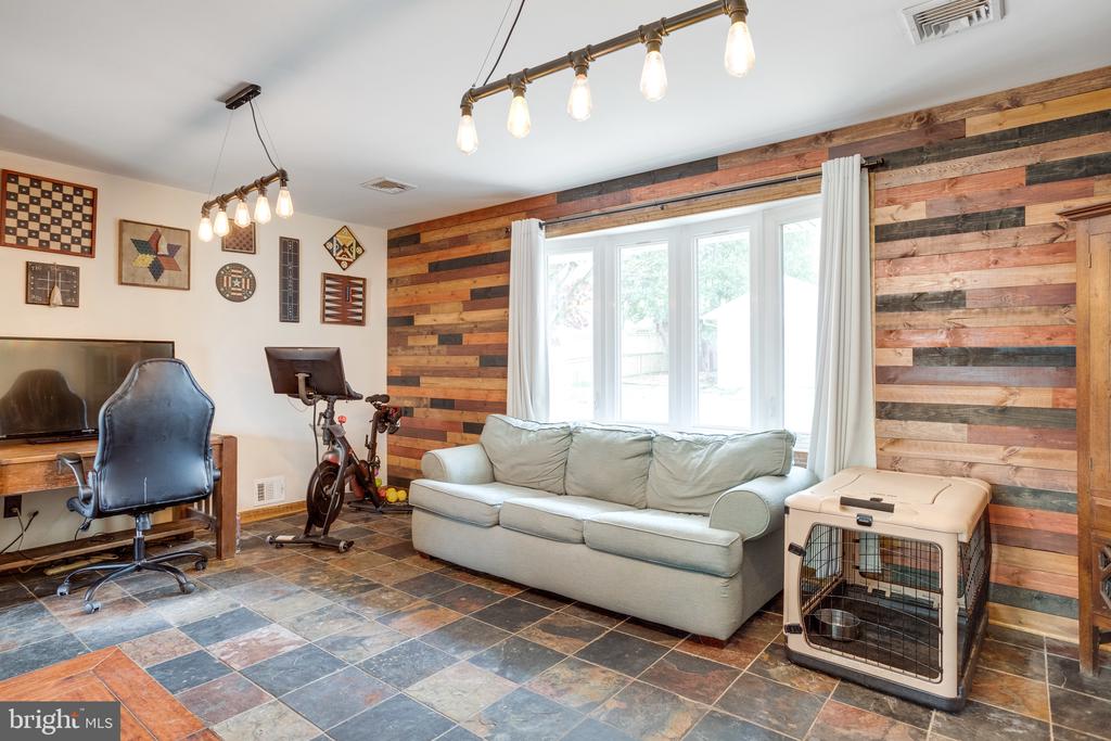 Furnished living room with a pale sofa, colorful wood accent wall, and large windows.