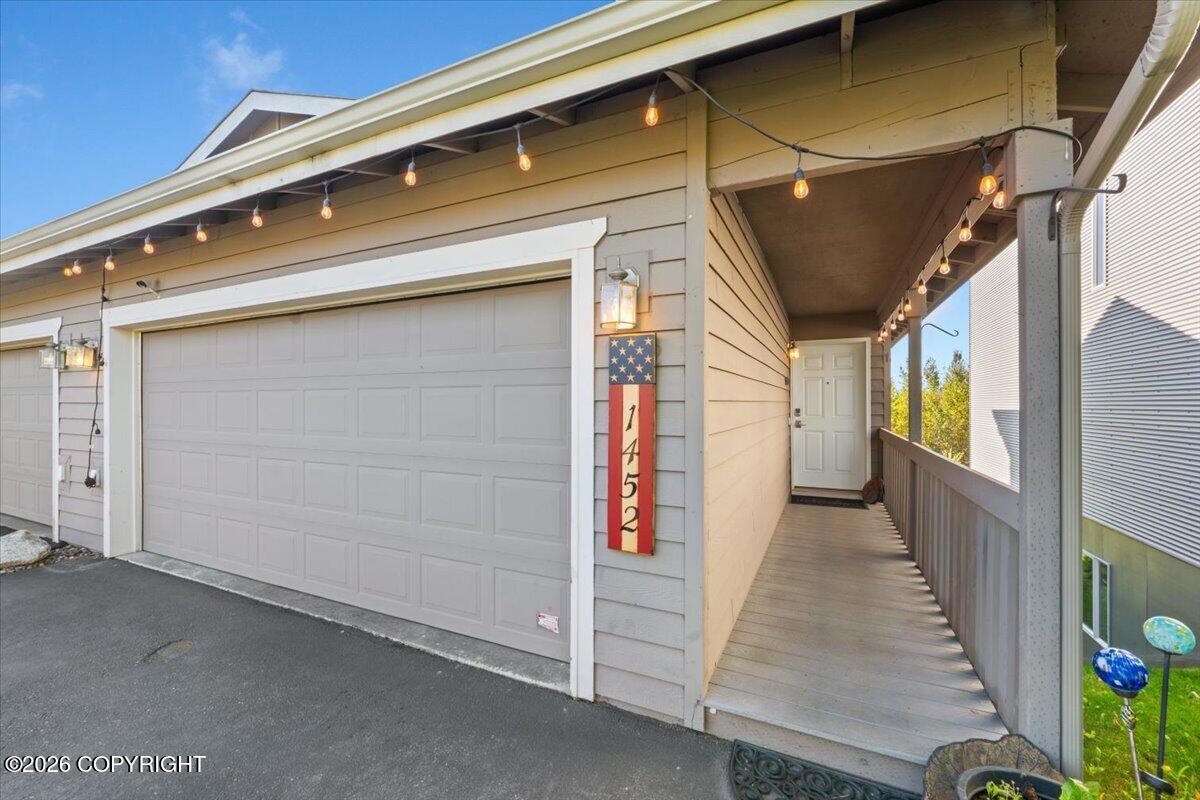 Home exterior with a large garage and covered walkway strung with lights.
