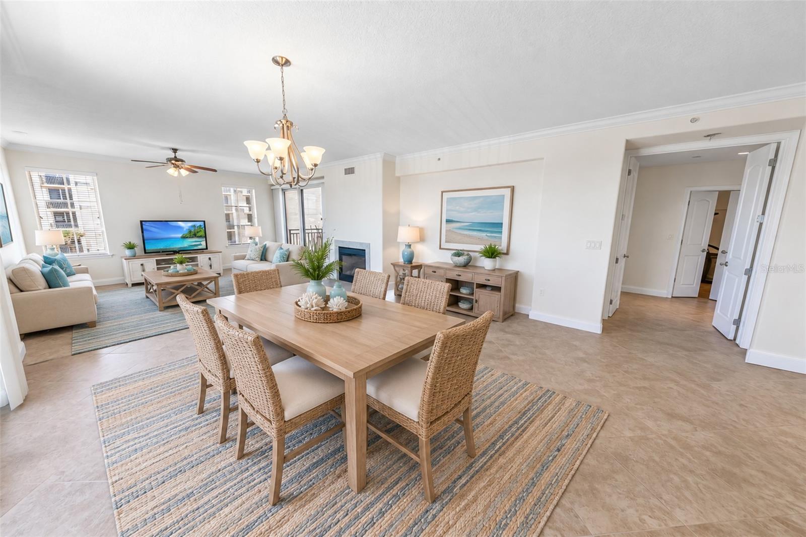 Open-plan condo dining and living room with woven chairs, a fireplace, and bright windows.