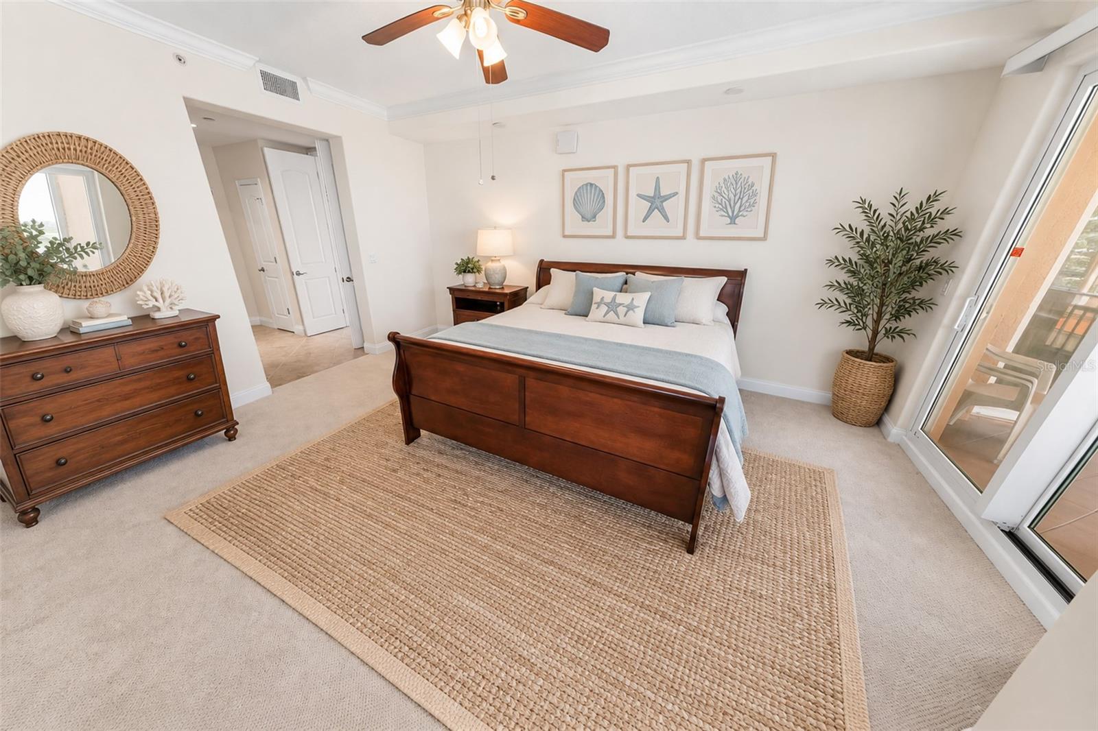 Furnished bedroom with coastal decor and sliding glass doors to a balcony.