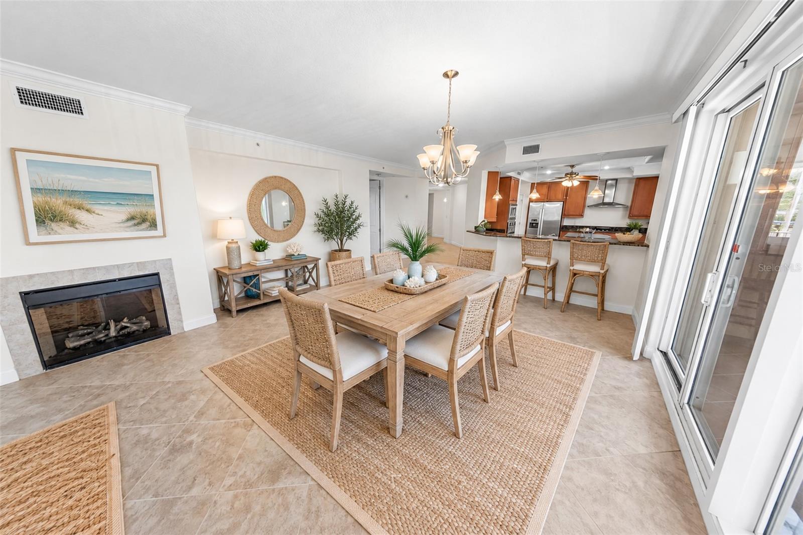 Staged condo dining room with a wood table, fireplace, and open kitchen.