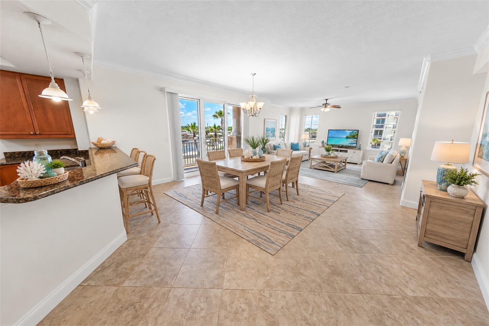 Open-plan condo living and dining area with a kitchen peninsula and sliding doors to a balcony.