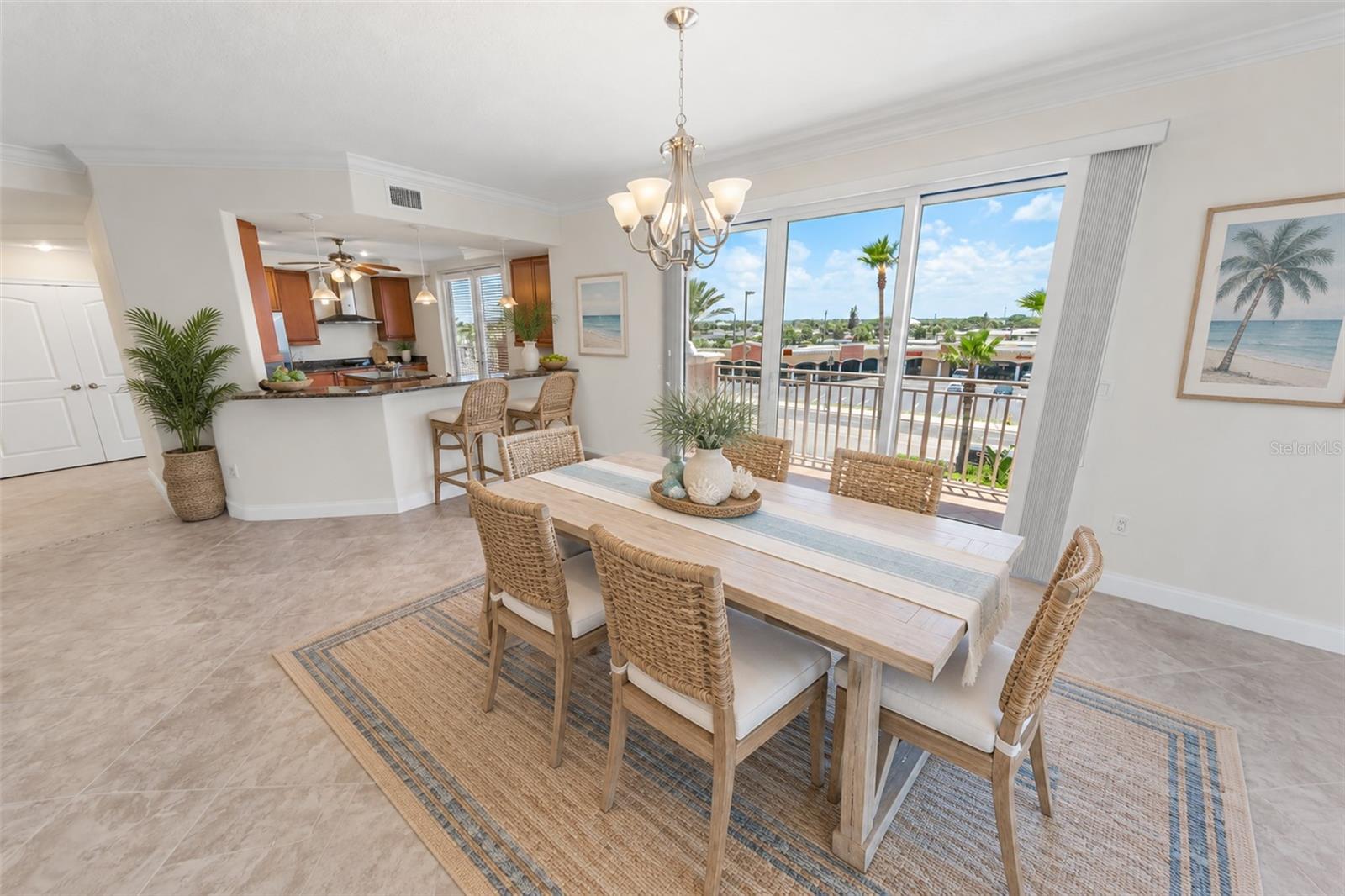 Dining area with a long wicker-chair table, open kitchen, and sliding doors to a balcony.