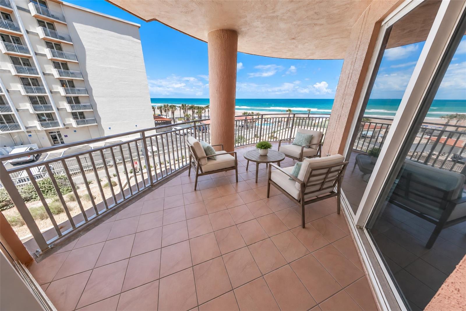 Furnished oceanfront balcony with seating and a wide view of the beach and Atlantic Ocean.