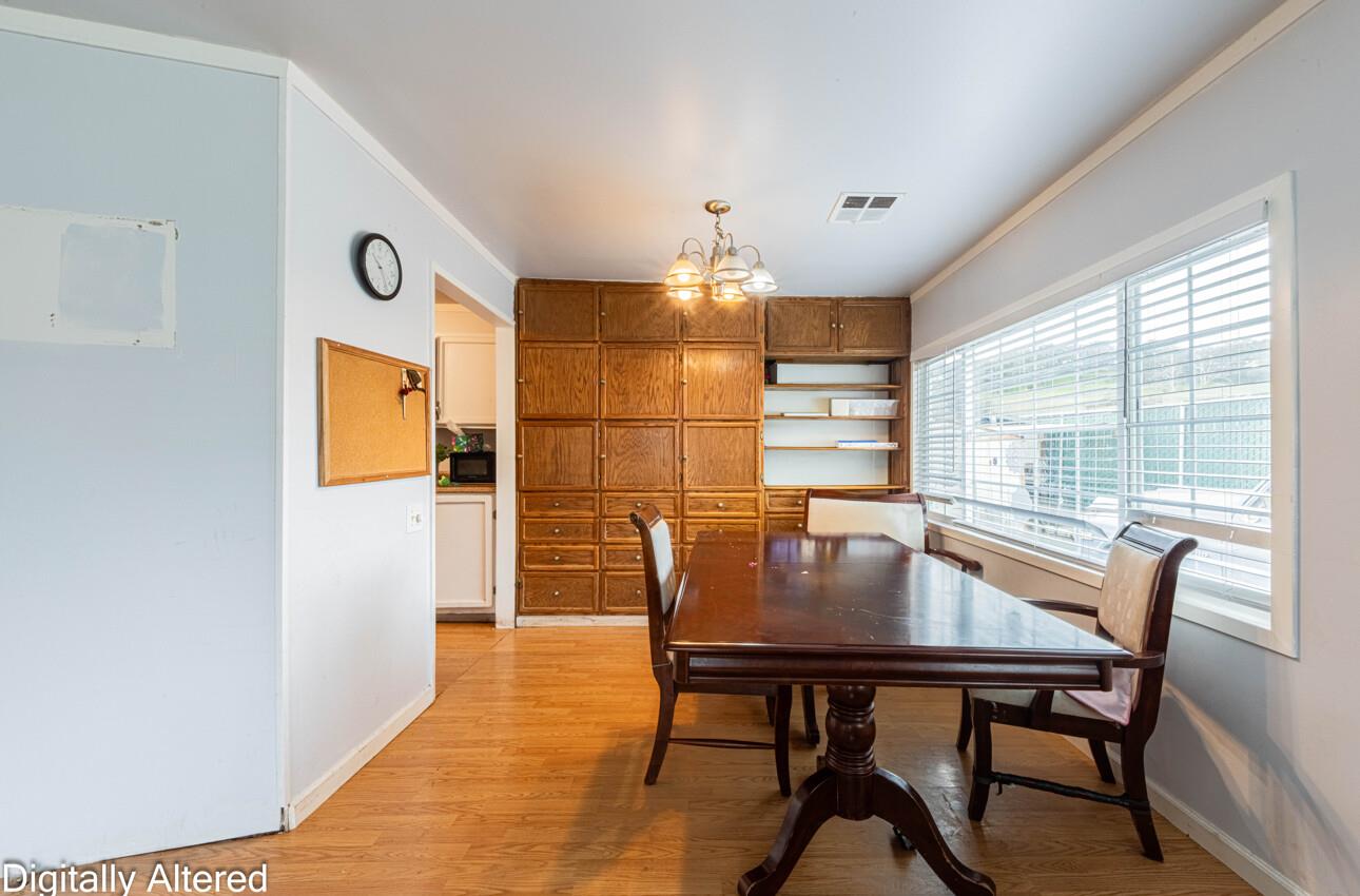 Dining room with built-in wooden cabinets, a dark table, and large windows with blinds.