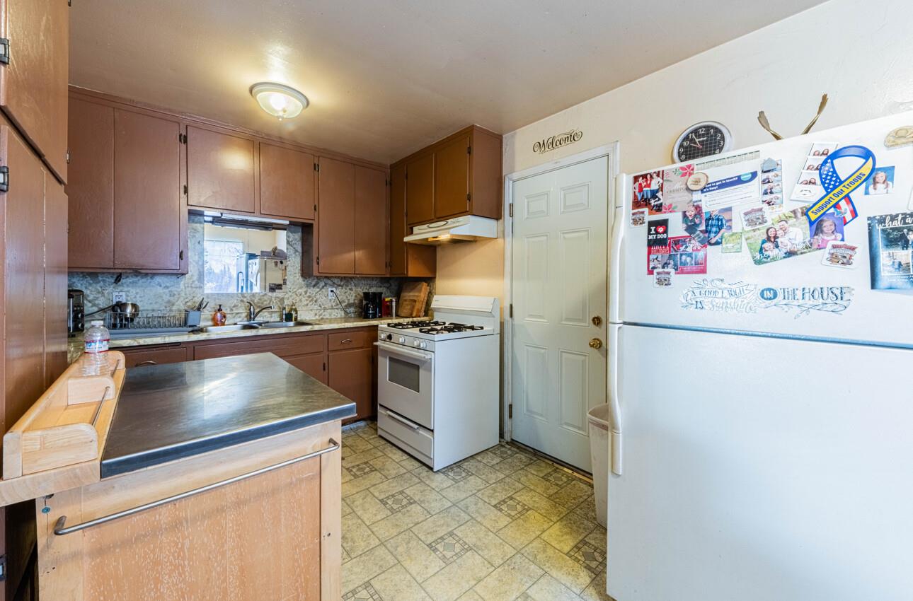 Kitchen with brown cabinets, patterned tile flooring, and a refrigerator covered in photos and magnets.