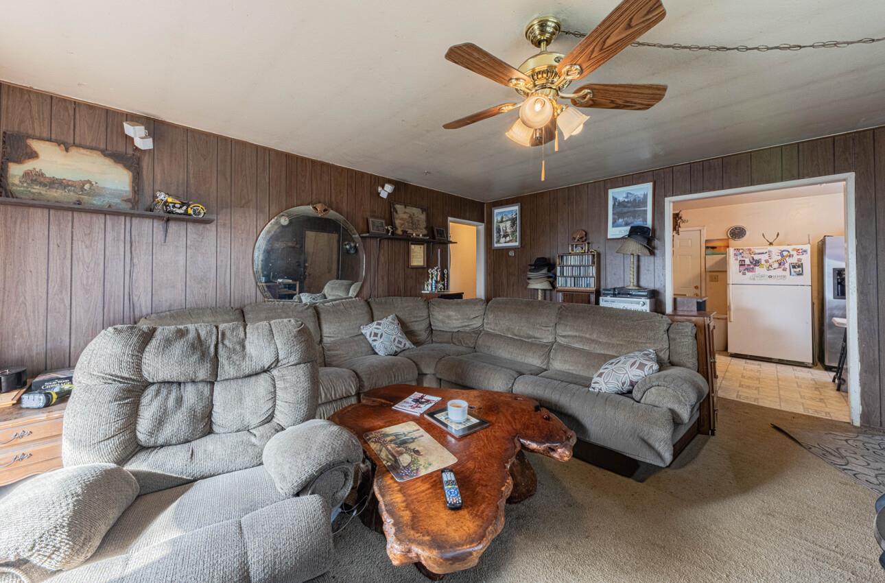 Living room with a gray sectional, live-edge coffee table, and dark wood-paneled walls.