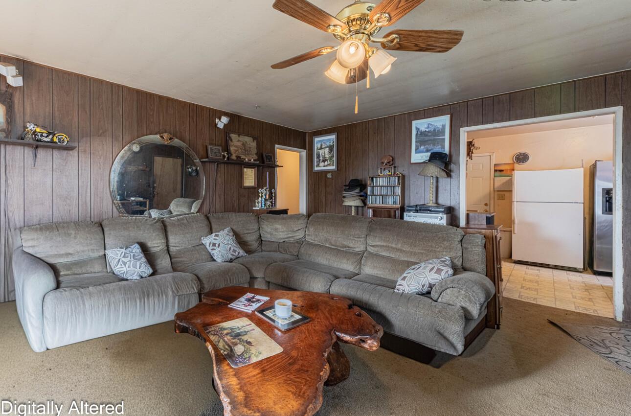 Living room with a gray sectional, wood-paneled walls, and a live-edge coffee table.