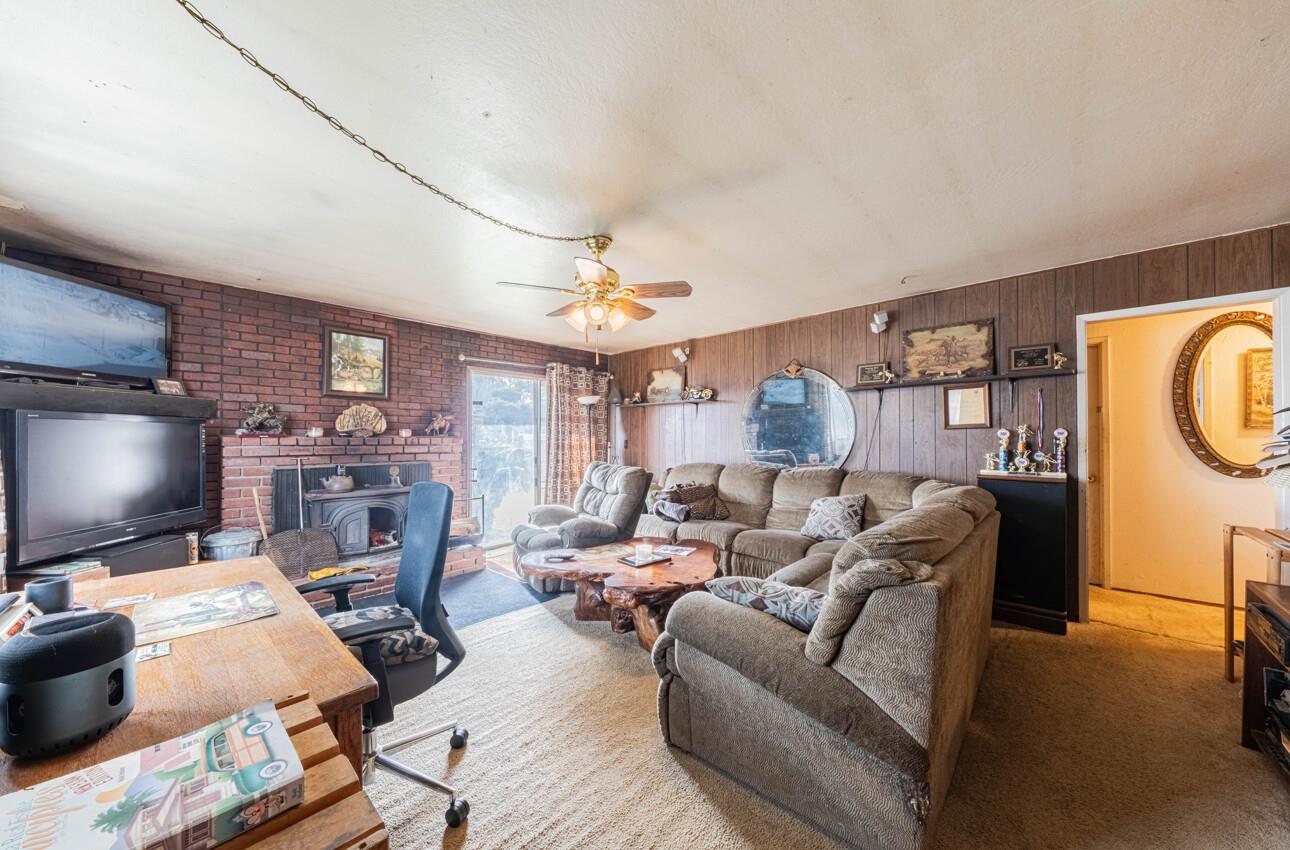 Living room with a brick fireplace, wood-paneled walls, and a large sectional sofa.