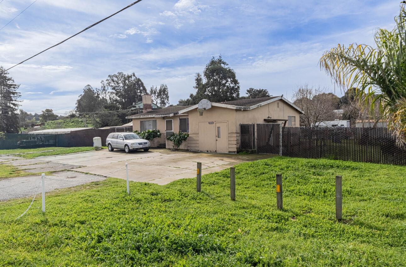 Single-story tan house with a basketball hoop, concrete driveway, and fenced grassy yard.