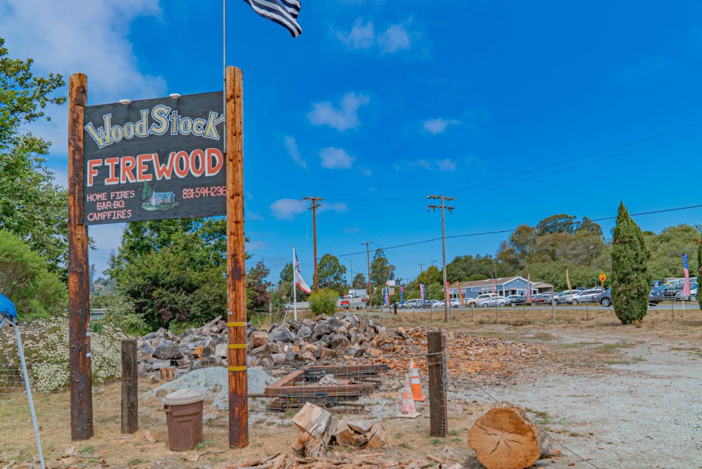 WoodStock firewood yard with a large roadside sign and piles of split logs.