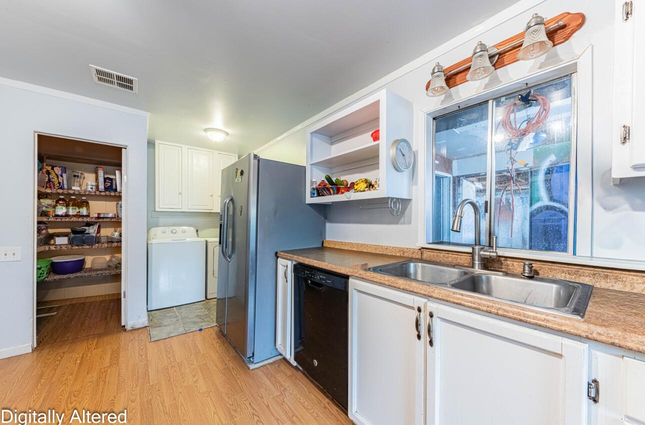 Kitchen with a double-basin sink, stainless-steel refrigerator, and adjoining pantry and laundry area.