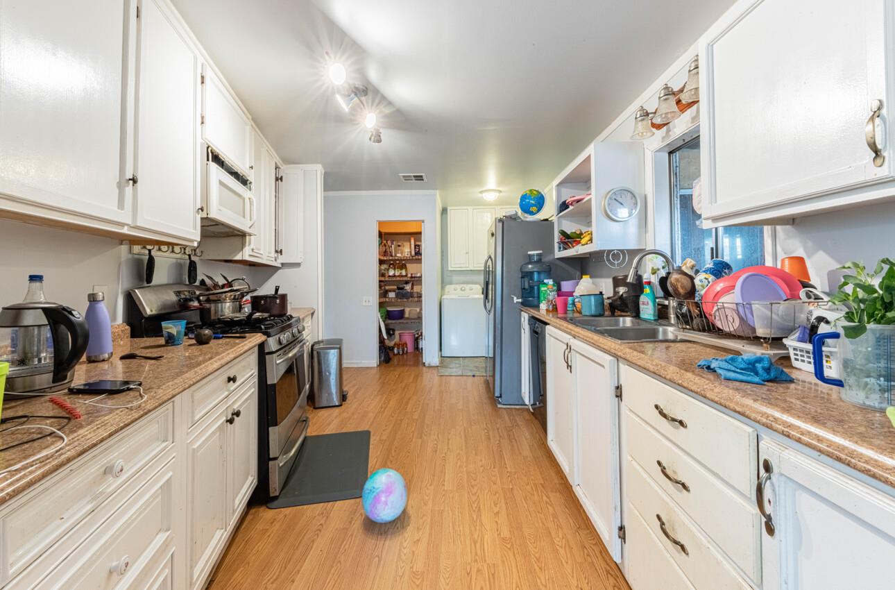 Galley kitchen with white cabinets, granite counters, and stainless steel appliances.
