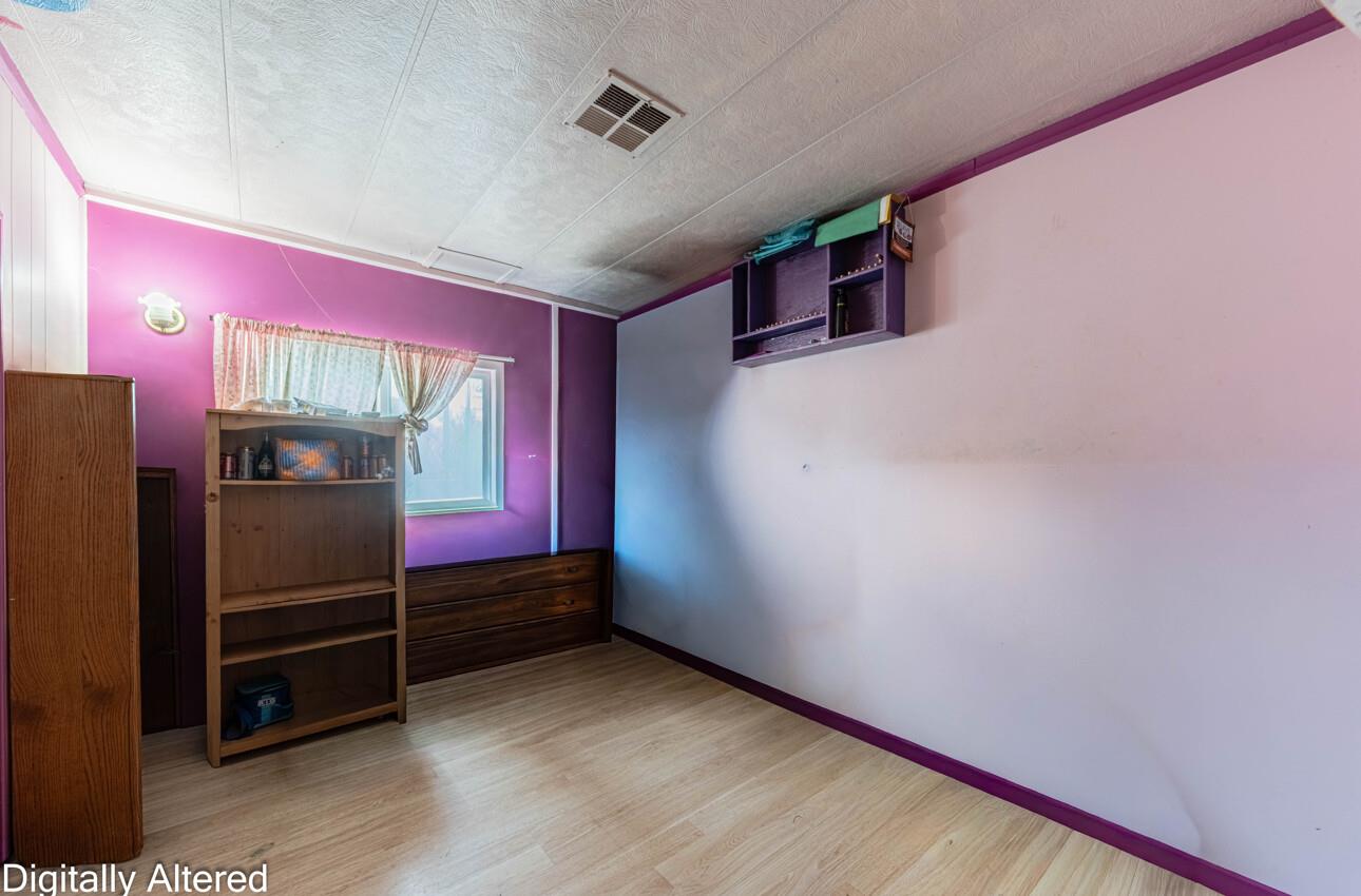 Bedroom with purple walls, light wood flooring, a curtained window, and wooden shelving.