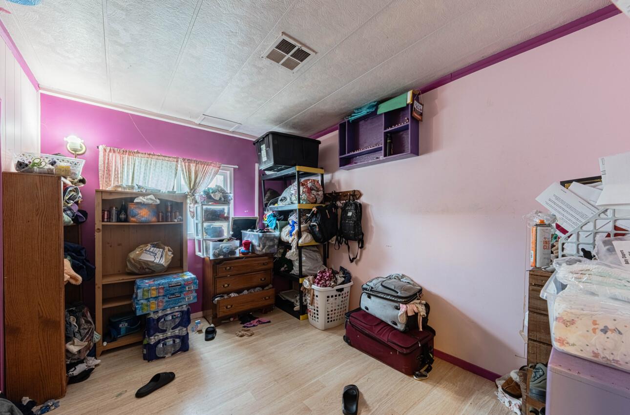 Cluttered storage room with pink walls, packed shelving, and stacked suitcases.