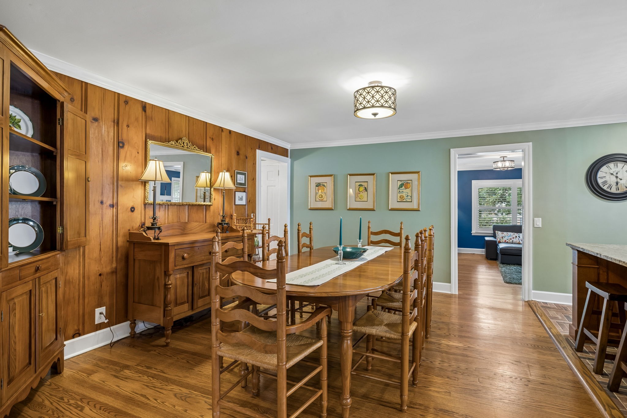 Dining room with a wooden table, paneled walls, built-in cabinetry, and hardwood floors.