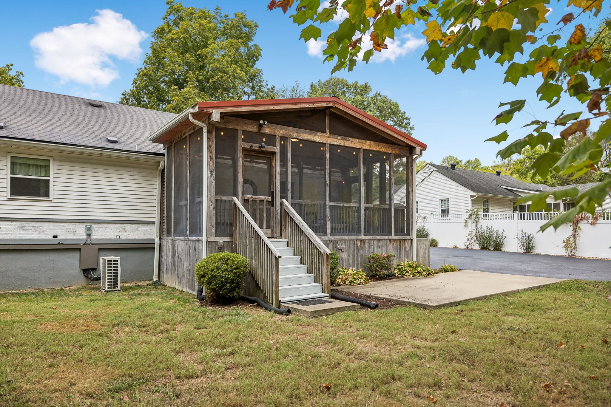 House with a large screened porch and central wooden stairs opening onto a lawn.
