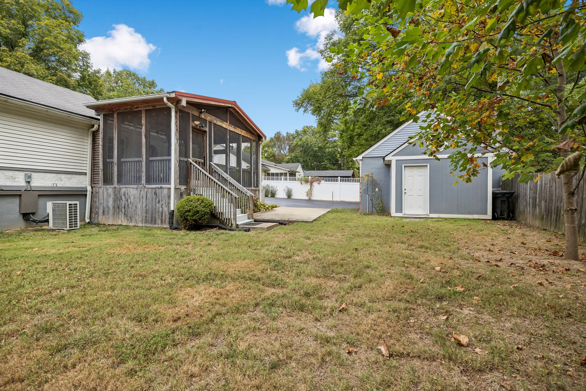 Backyard with a screened porch, detached gray shed, and mature trees.