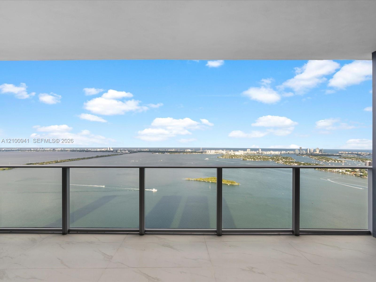 High-rise balcony overlooking Biscayne Bay, with islands and Miami’s distant skyline.
