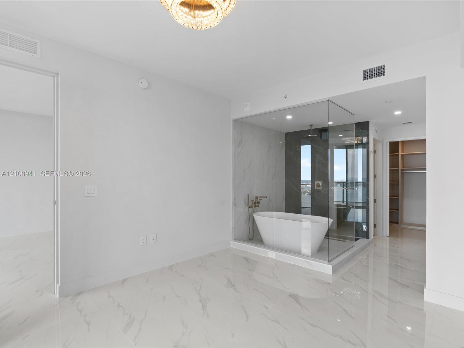Modern bathroom with a freestanding tub in a glass-enclosed shower and water visible through the windows.