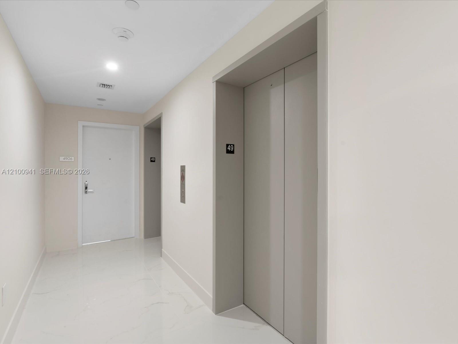 Condo hallway with elevator doors marked 49 and unit 4906’s entry door.