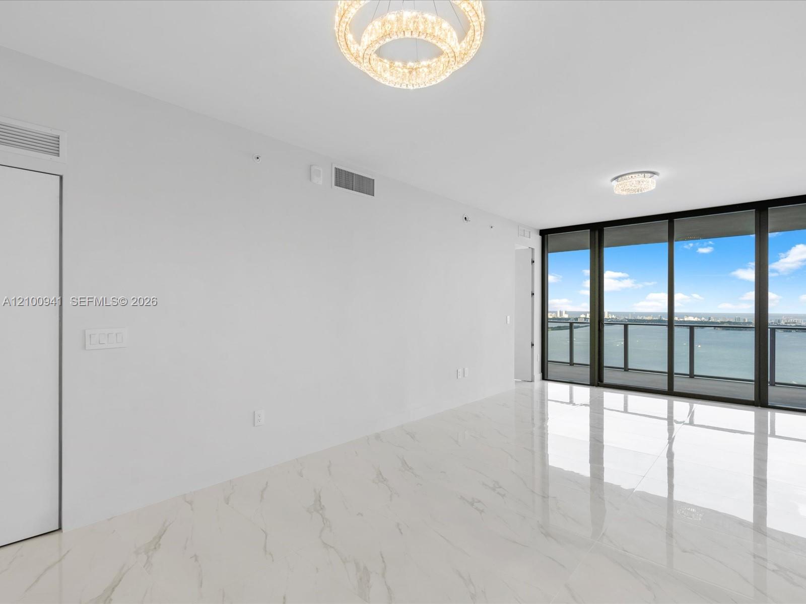 Vacant condo living area with glossy marble-look floors and floor-to-ceiling windows overlooking the bay.