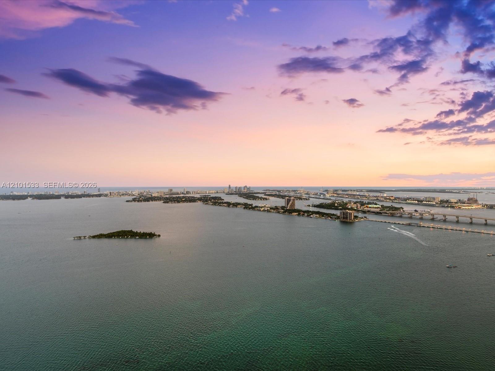 Aerial view over Biscayne Bay and Miami’s waterfront skyline at sunset.