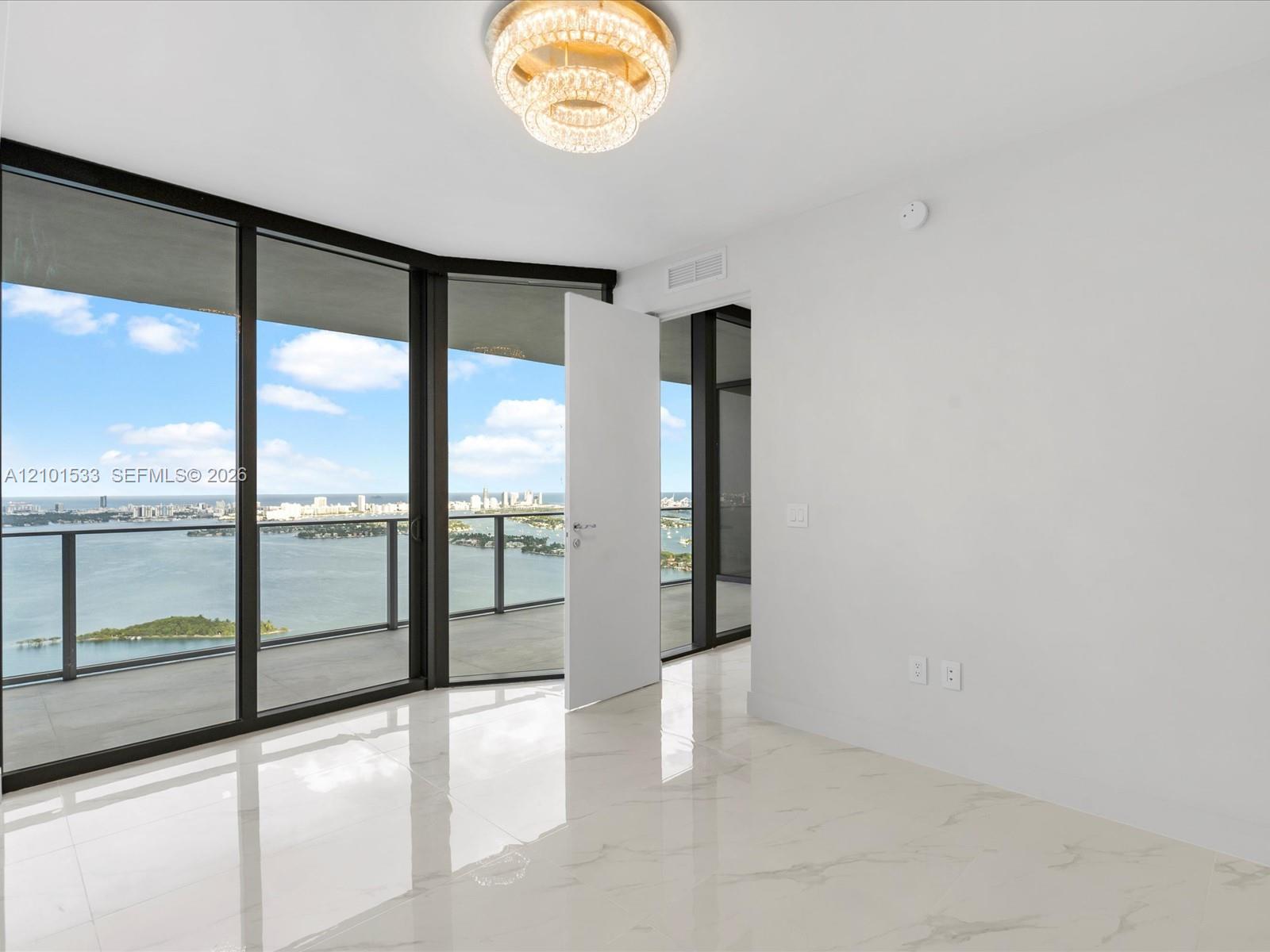 Empty condo room with floor-to-ceiling windows overlooking Biscayne Bay and the Miami skyline.