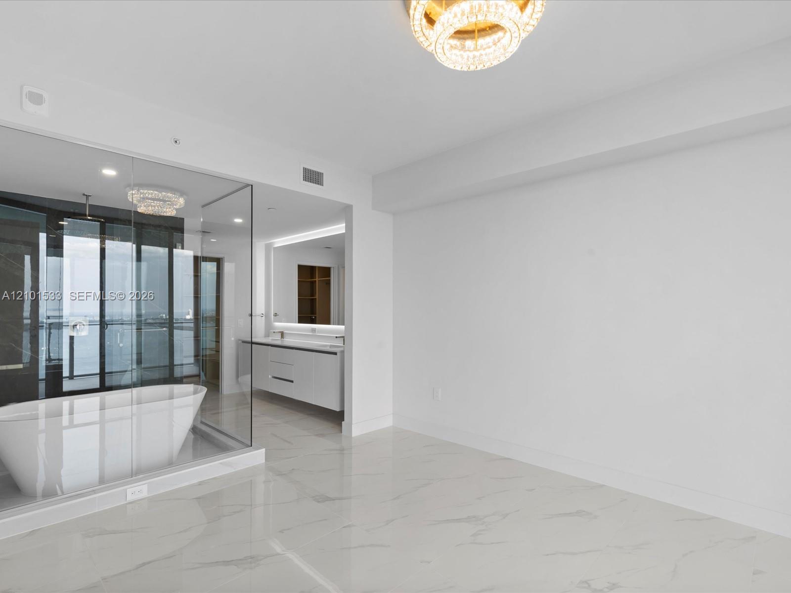 Modern bathroom with a glass-enclosed freestanding tub, floating vanity, and marble-look tile floor.
