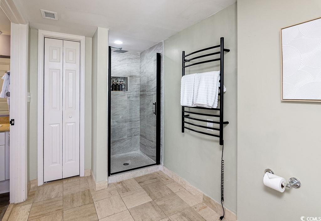 Bathroom with a gray-tiled walk-in shower and black heated towel rack.
