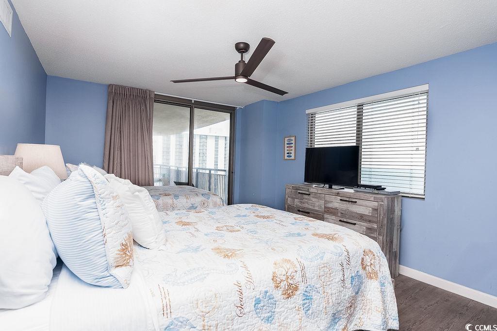 Furnished bedroom with two beds, blue walls, and a sliding glass door to the balcony.