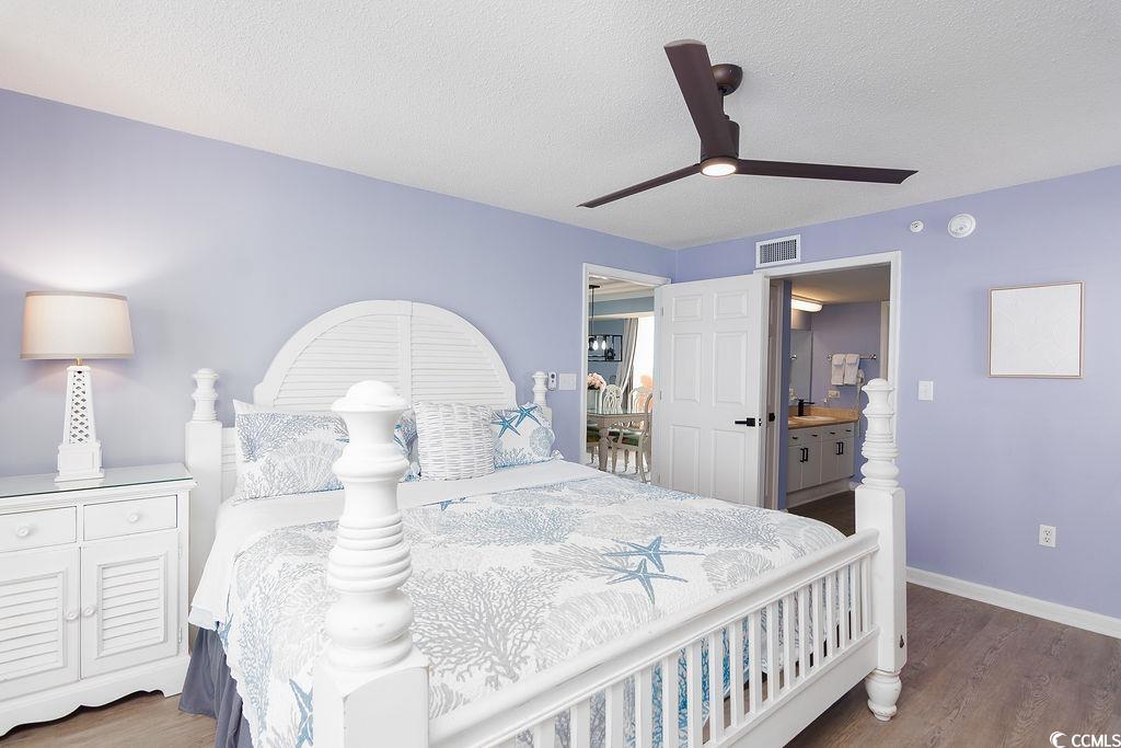 Furnished bedroom with lavender walls, a white four-poster bed, and coastal-patterned bedding.