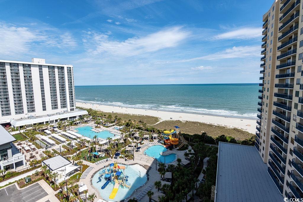 Oceanfront resort view with pools, sandy beach, and ocean between condominium towers.