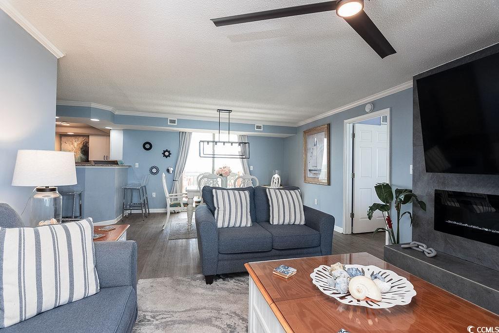 Furnished living room with blue sofas, a fireplace and an open dining area and kitchen.