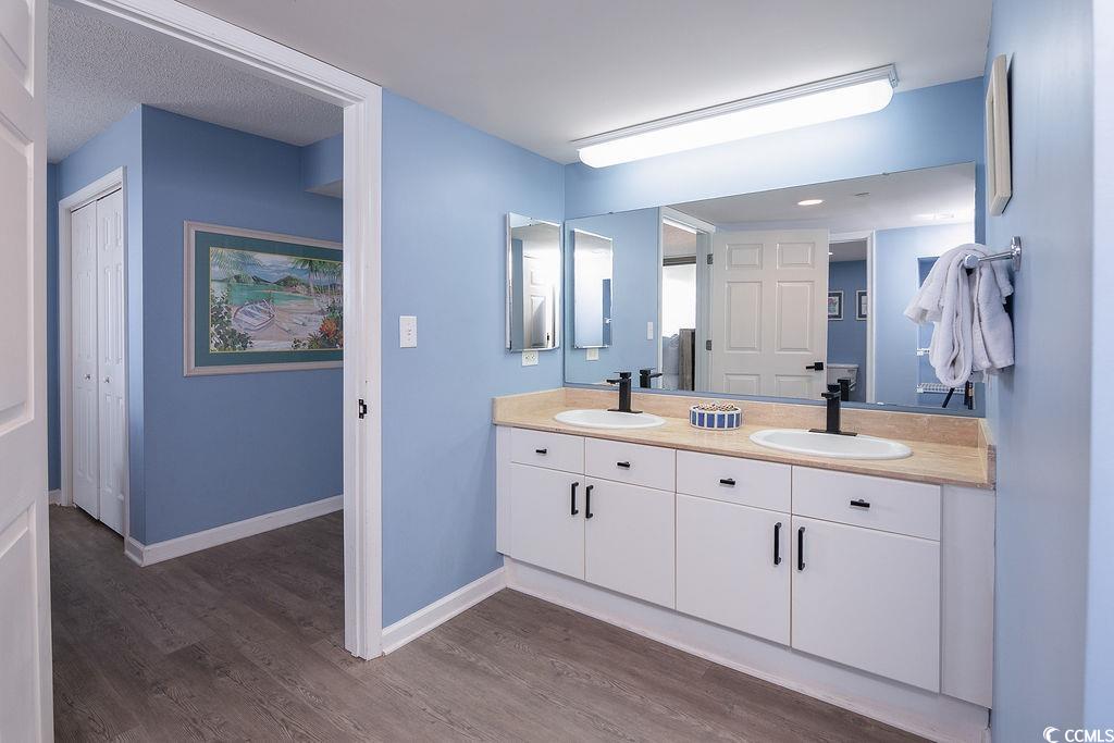 Bathroom with a white double vanity, black faucets, broad mirrors, and pale blue walls.