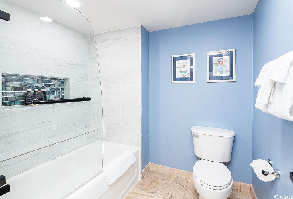 Bathroom with a tiled tub and glass shower, mosaic niche, and blue walls.