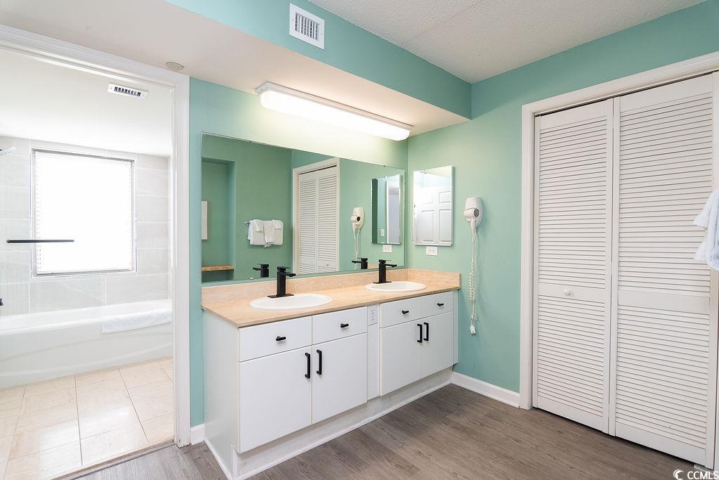Bathroom with double vanity, teal walls, mirrored backsplash, and an adjoining tiled tub area.