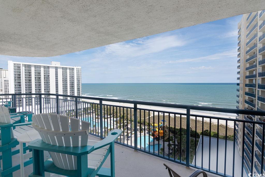 Condominium balcony with Adirondack chairs overlooking the ocean, beach, and pool.