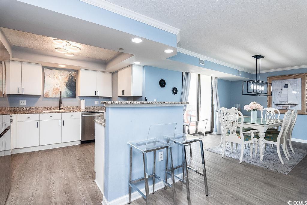 Open-plan kitchen and dining area with a breakfast bar, white cabinetry, and nautical artwork.