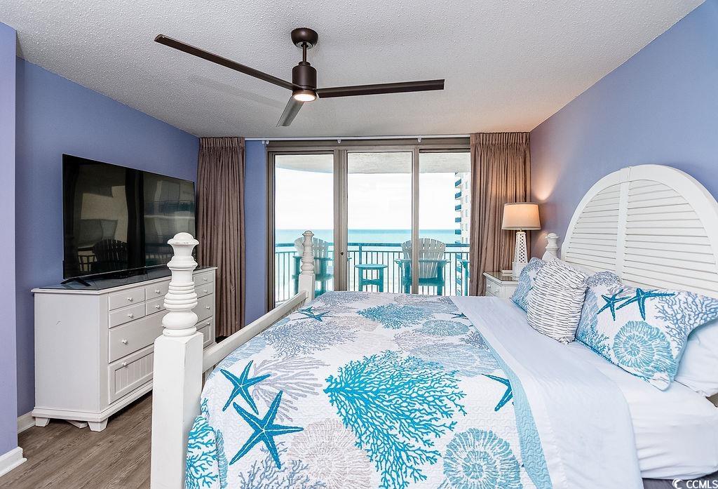 Bedroom with blue coastal bedding and sliding doors opening to a balcony overlooking the ocean.