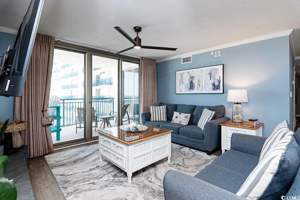 Condominium living room with blue sofas and sliding doors opening to a furnished balcony.