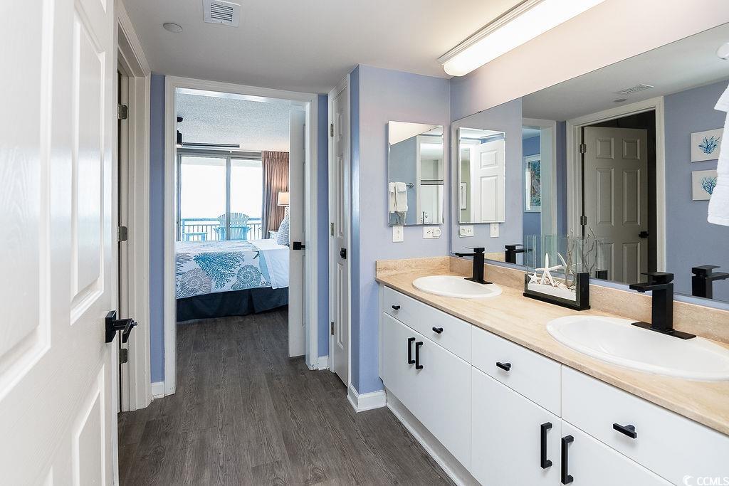 Bathroom with a double-sink vanity and a view through to a bedroom and balcony.