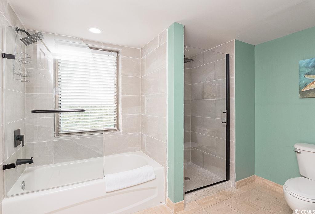 Bathroom with a tiled tub, glass-enclosed shower, black fixtures, and mint-green walls.