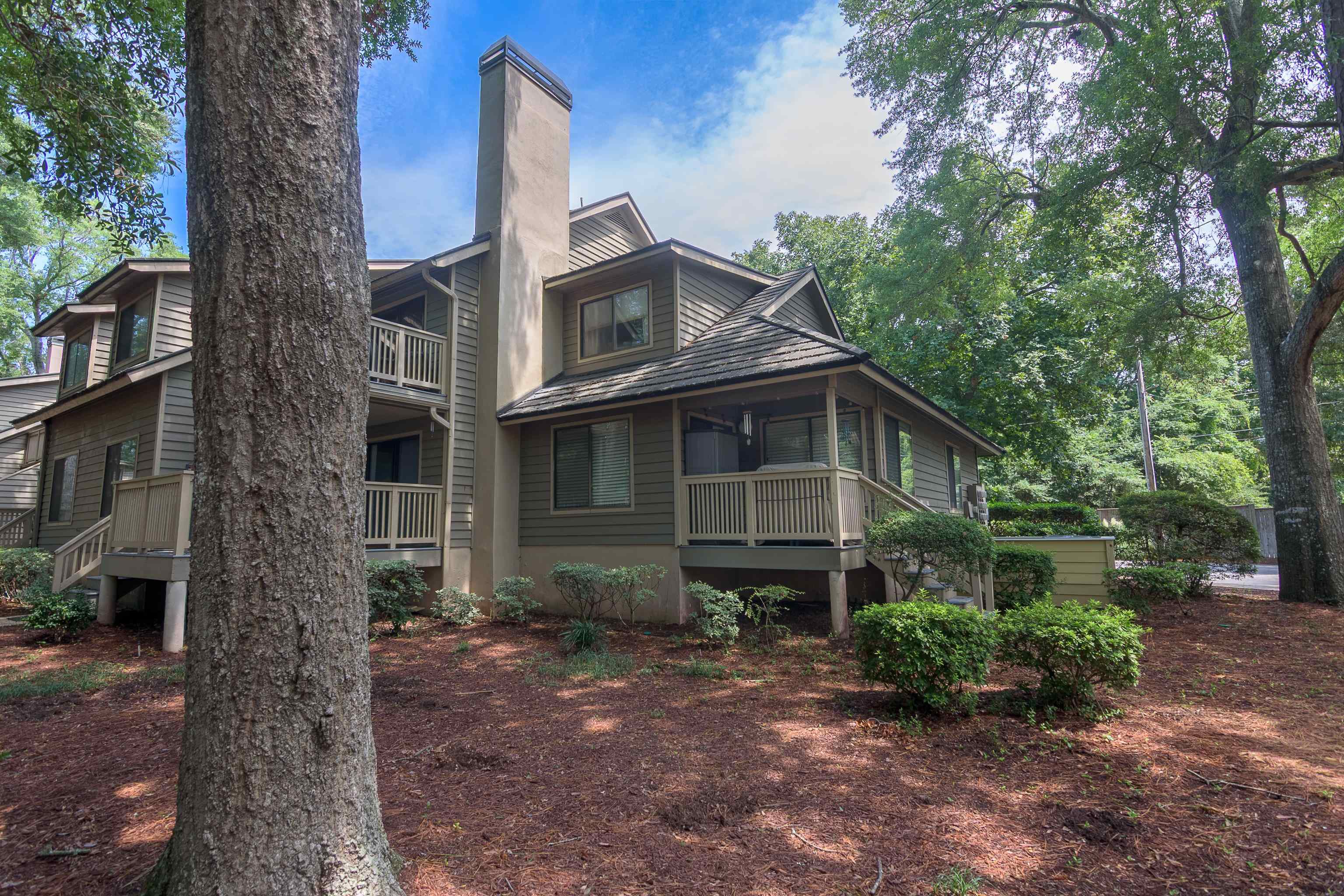 Townhouse exterior with raised balconies, a prominent chimney, and mature trees.